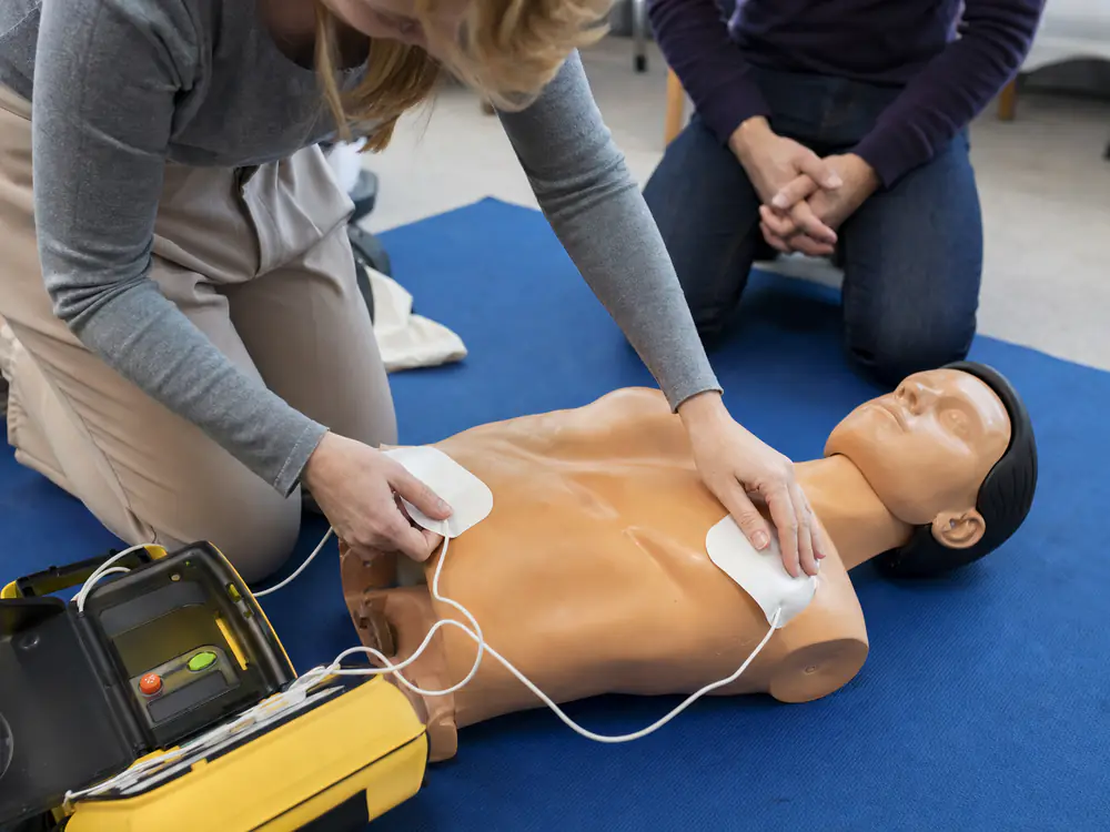 Cursisten plakken de elektroden van een AED-trainer op een oefenpop