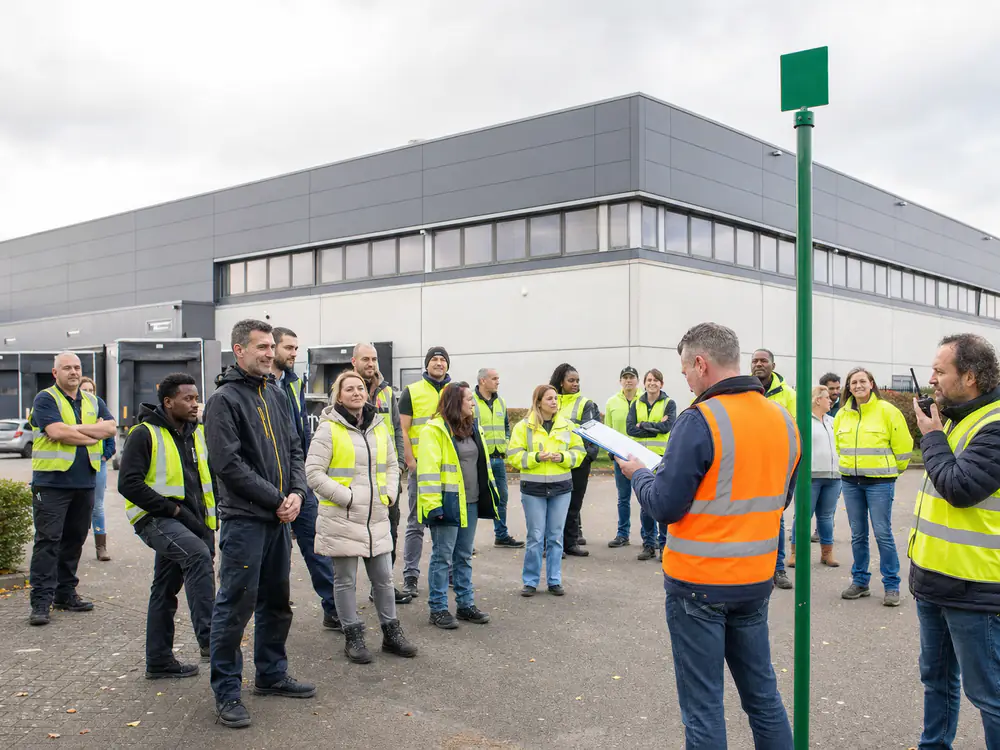Ploegleider telt medewerkers op de verzamelplaats tijdens een ontruimingsoefening