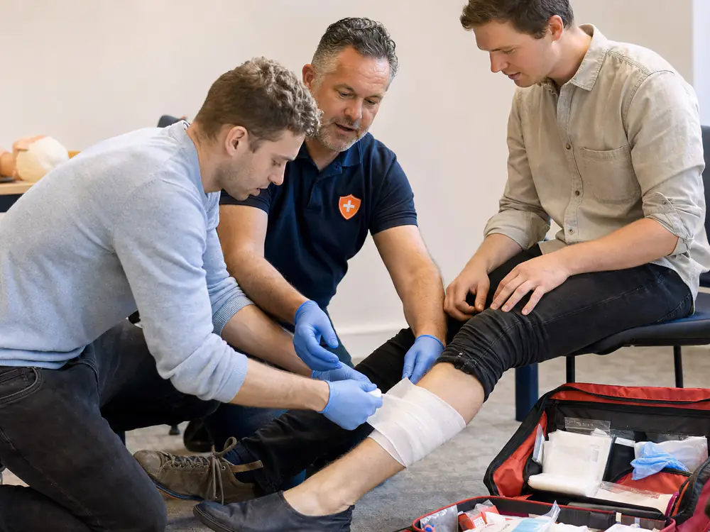Cursist legt een drukverband aan bij een collega tijdens de training BHV en EHBO